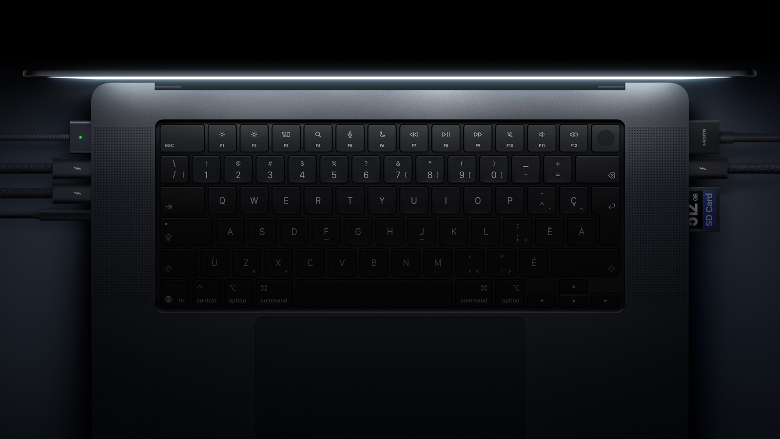 Draufsicht auf Tastatur und seitliche Anschlüsse eines MacBook Pro mit angeschlossenen Kabeln und einer SD-Karte.